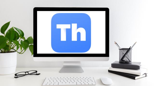 Un grand écran d'ordinateur affichant le logo Thorium est posé sur un bureau blanc avec un clavier et une souris devant lui. Une plante, des lunettes, une pile de cahiers et une tasse contenant des stylos et des crayons se trouvent également sur le bureau.