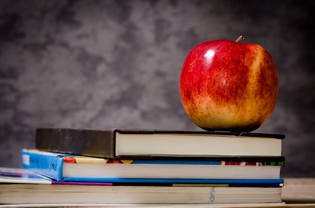 A teacher's desk, apple and books