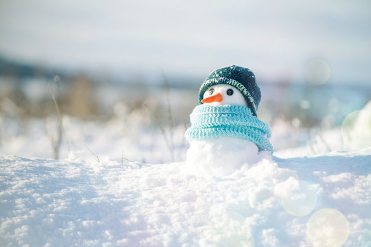 A snowman wearing a blue scarf and tuque.