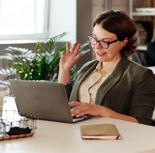 Une femme qui porte des lunettes fait une présentation devant son ordinateur portable