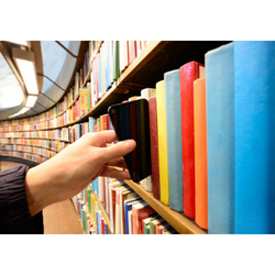 Une main atteint une étagère de bibliothèque remplie de livres colorés et en sort un téléphone portable