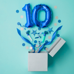 des ballons en forme de chiffre 10 semblent exploser hors d'une boîte, suivis de confettis et de banderoles.