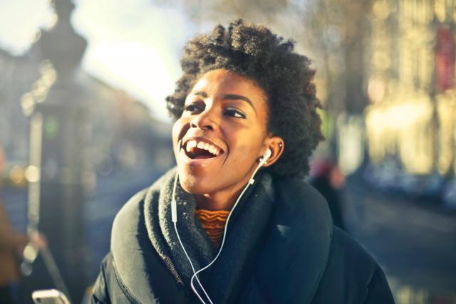 Image d'une femme souriante en écoutant un livre audio