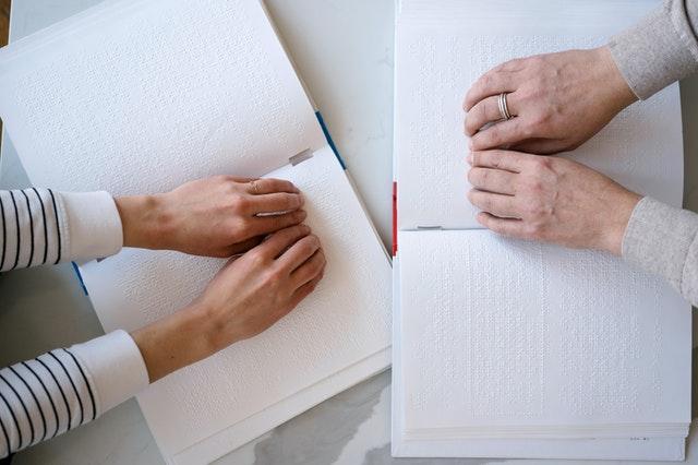 Two people reading two different braille books
