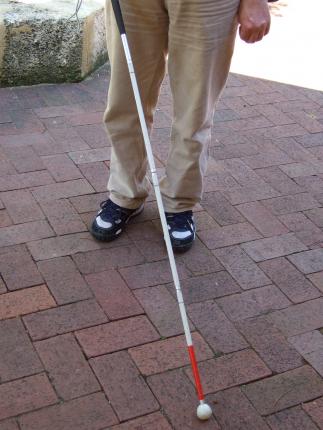 a man using a white cane to navigate a city streetwalk