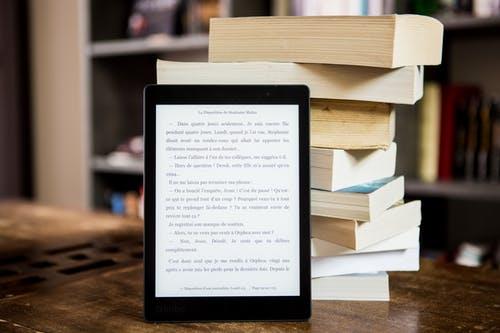 Tablet with text on the screen in front of a stack of books