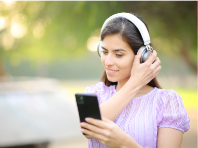 Une femme avec des écouteurs écoute un livre audio sur un téléphone.
